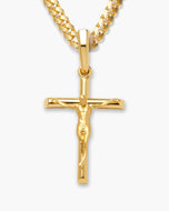 A gold crucifix pendant necklace featuring a detailed figure of Jesus on a polished cross, suspended from a thick curb chain against a light gray background.
