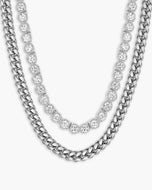 Two silver-toned necklaces on a light gray background: a Cuban link chain and a thinner tennis chain with round clear stones.